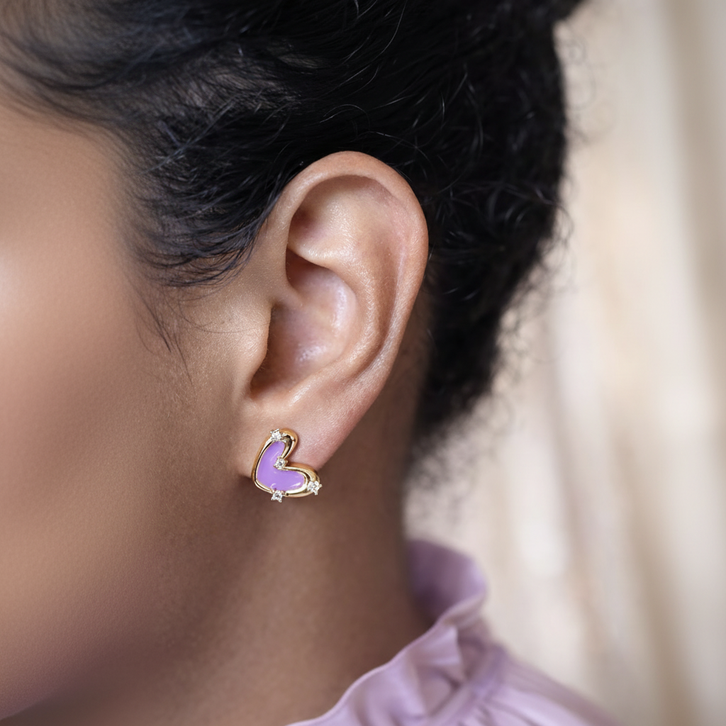Close-up of an ear wearing a purple heart-shaped earring with gold accents.