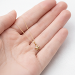 Gold star necklace held in a hand on a white background